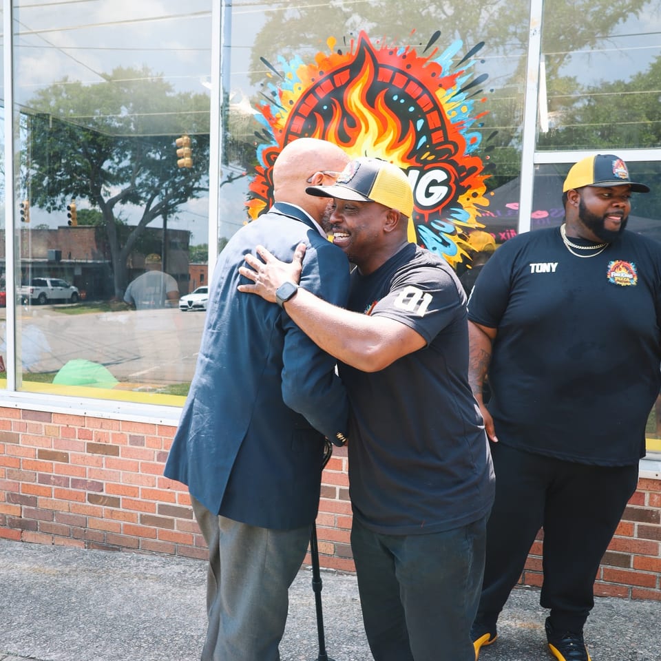 Fire King owner sharing a warm hug with a guest outside the Hampton Street storefront.
