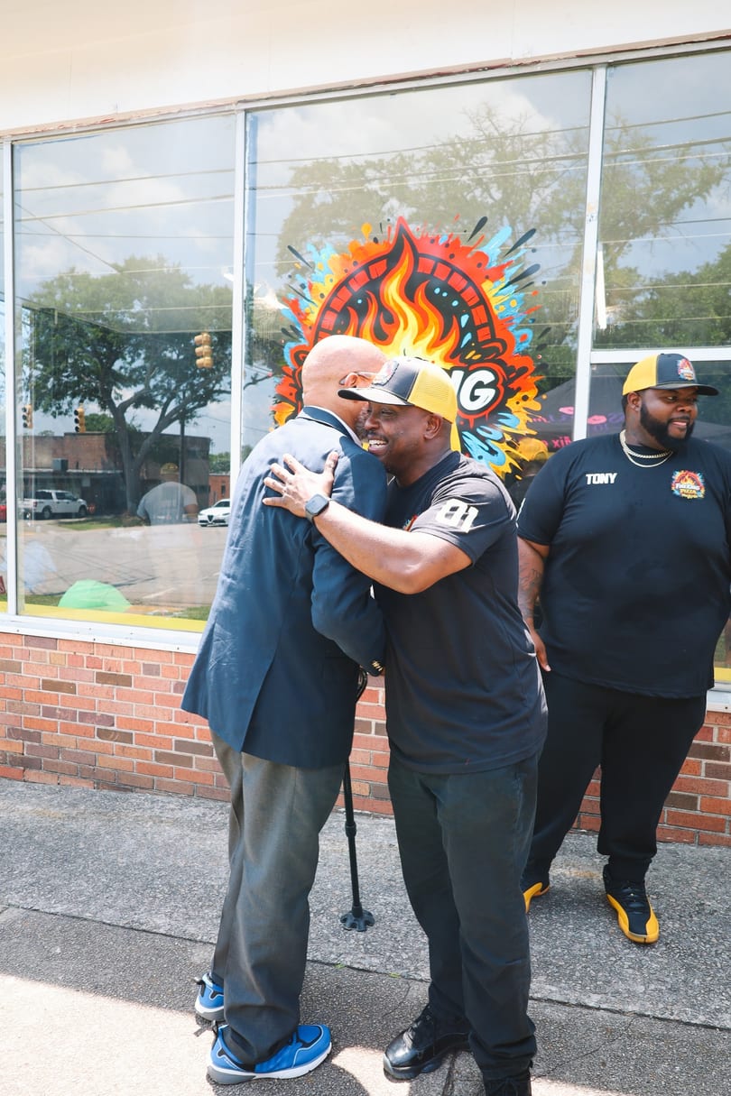 Fire King owner sharing a warm hug with a guest outside the Hampton Street storefront.