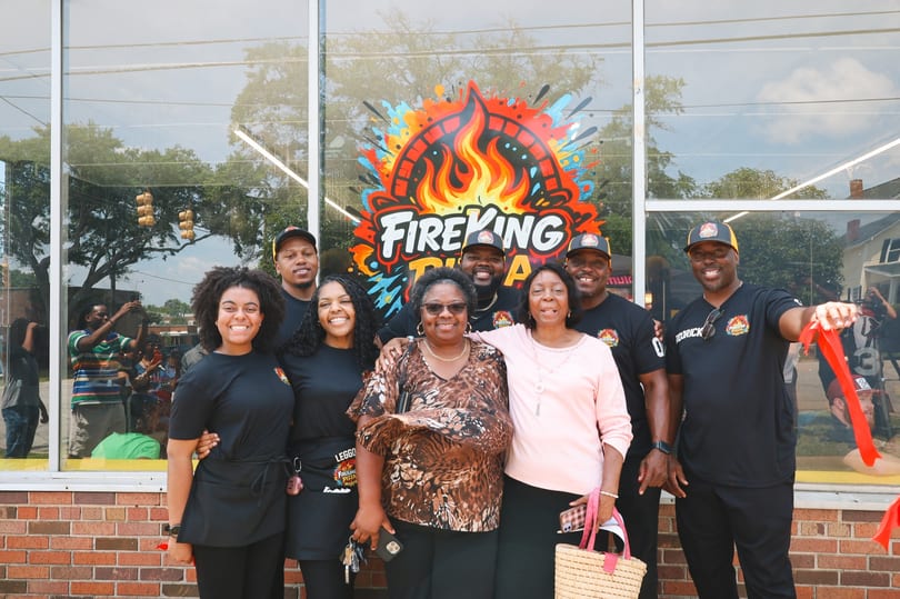 The Fire King family holding the red ribbon at the grand opening ribbon cutting.