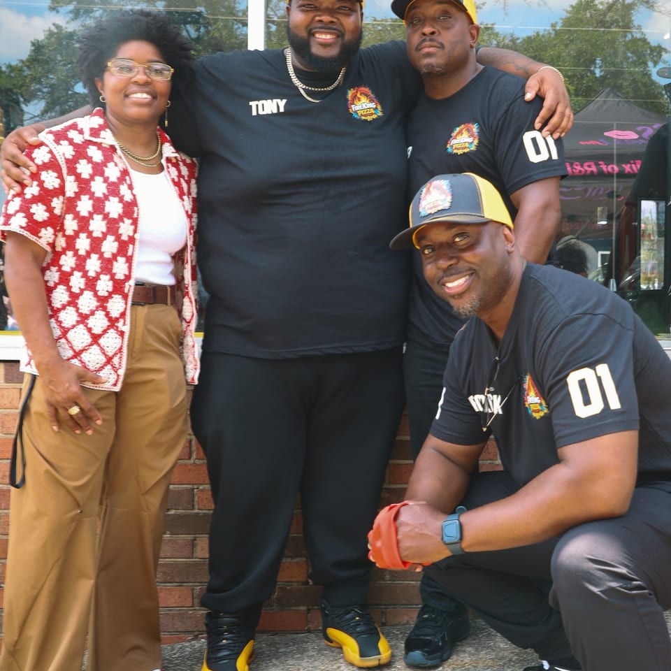 Four members of the Fire King team smiling together against the brick storefront.