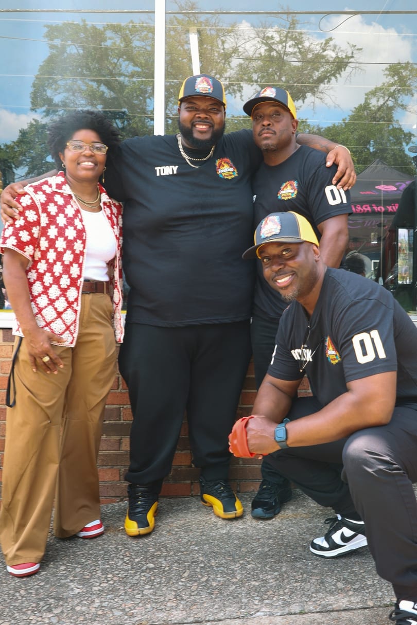 Four members of the Fire King team smiling together against the brick storefront.