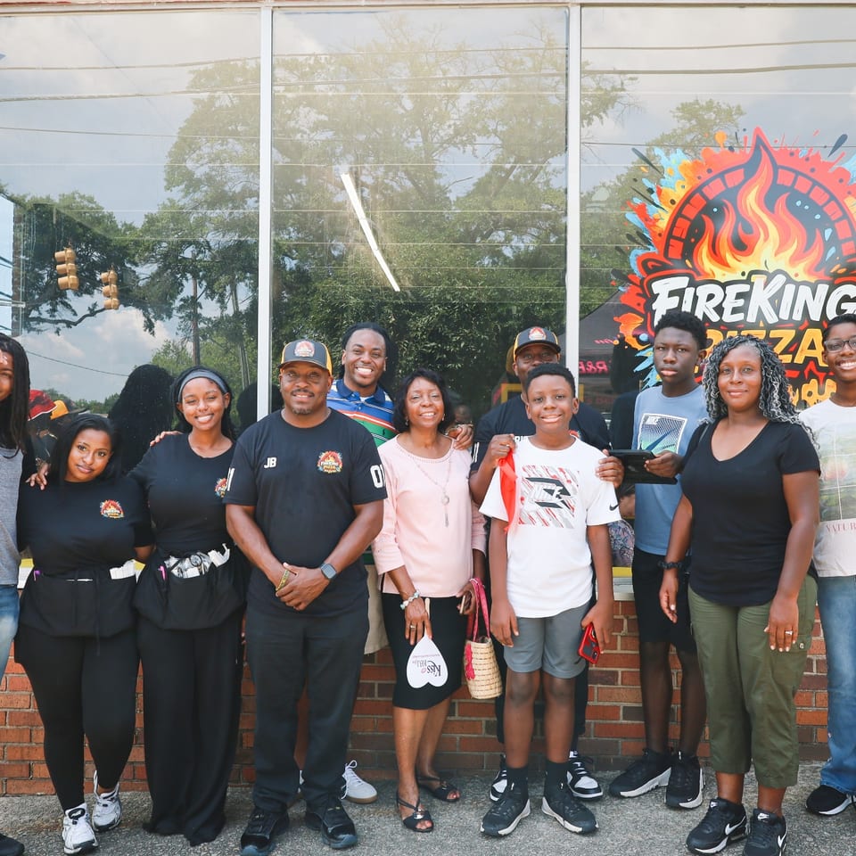 A large group of family and friends gathered in front of Fire King Pizza.