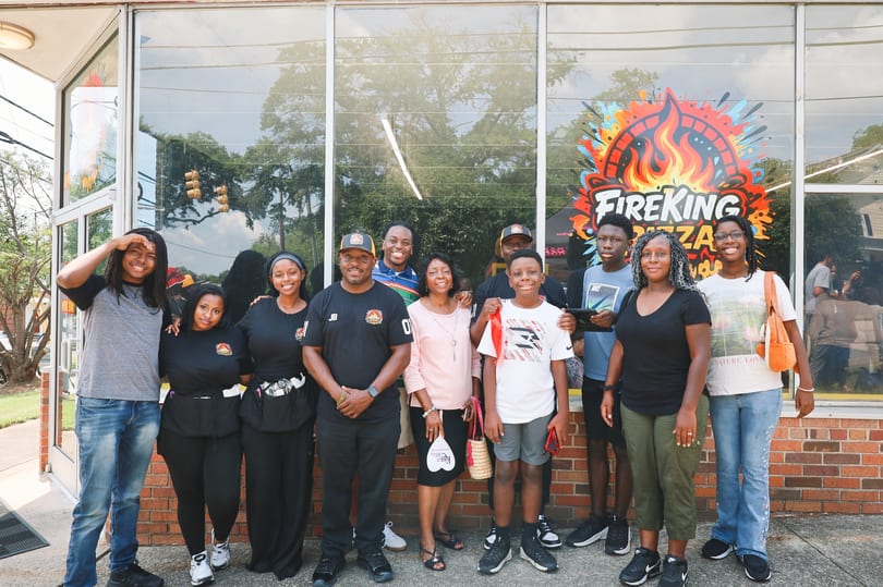 A large group of family and friends gathered in front of Fire King Pizza.